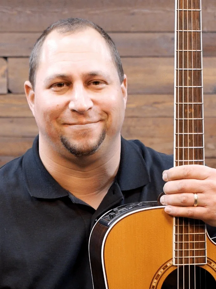 Jonathan Boettcher holding his guitar, the teacher behind PlayGuitar.com.